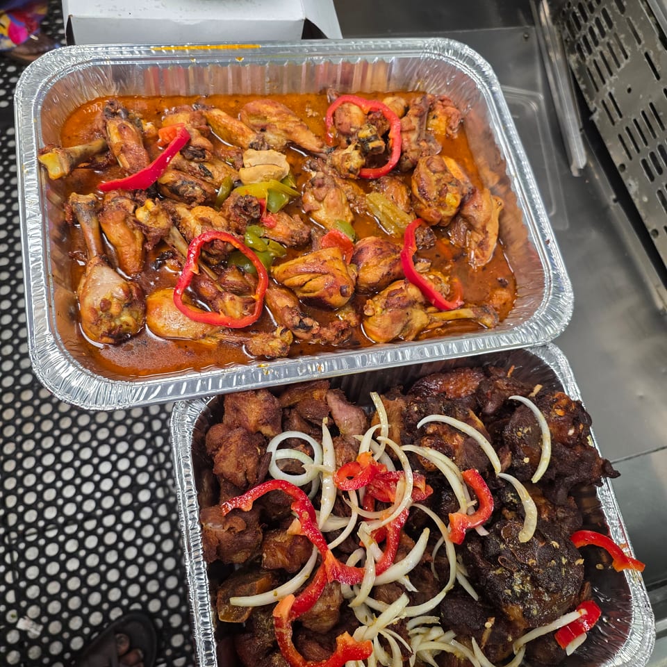 Aluminum trays display saucy chicken with peppers and fried meat garnished with sliced onions and red peppers.